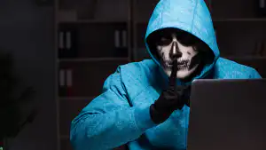 Hooded person using a laptop to represent test hacks
