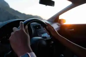 Driver holding the steering wheel at sunset
